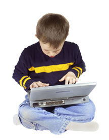Young boy sitting crossed legged using wireless laptop